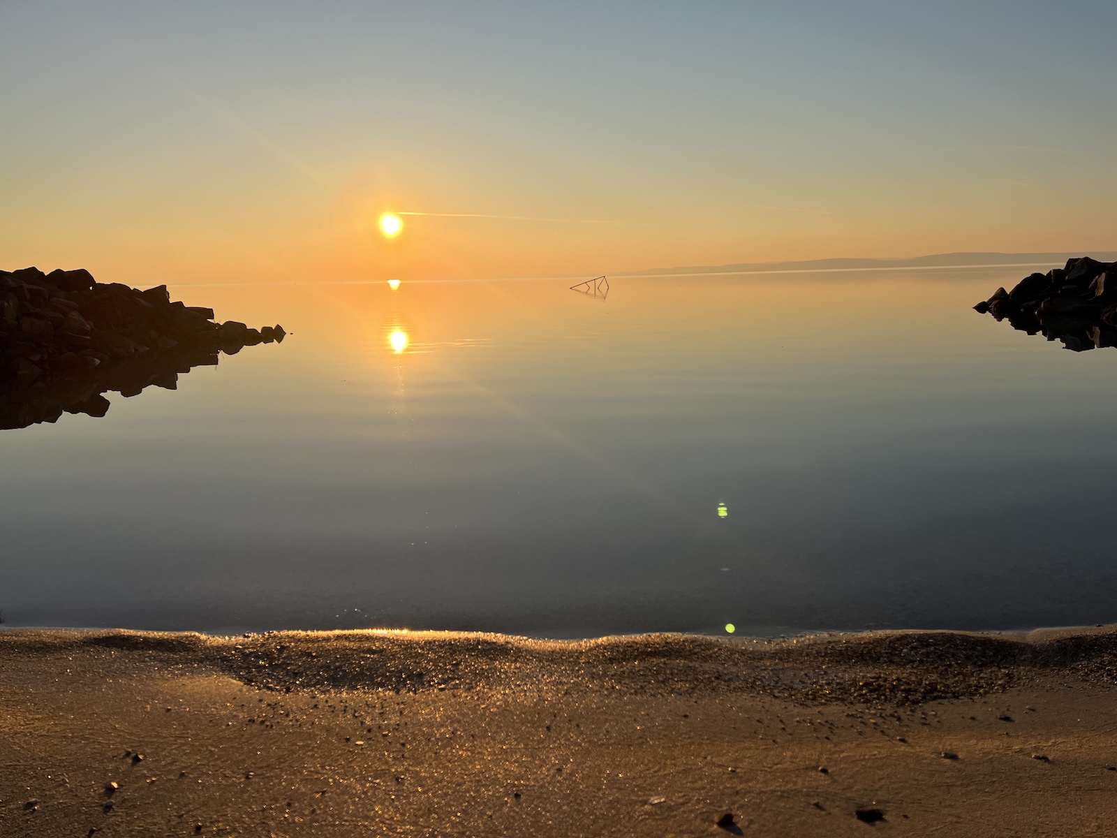 Sunset by the shore of Balaton with warm light and a pier